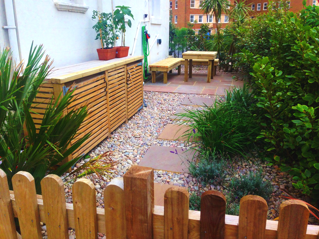 Coastal front garden in Hove designed to create a small patio terrace area set amongst lush, mostly evergreen plants and chosen to increase privacy and for its coastal location.