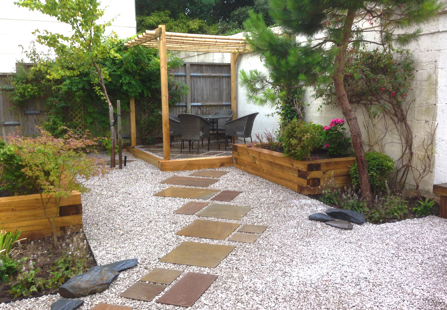 Courtyard garden in Brighton, with Japanese influences. Stones and rock lead to a raised patio with a bamboo pergola.
